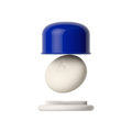 A close-up of a small personal care product with a glossy cobalt blue cap, a smooth off-white oval central piece embossed with a lowercase 'b', and a white bristle base, shown against a solid black background.