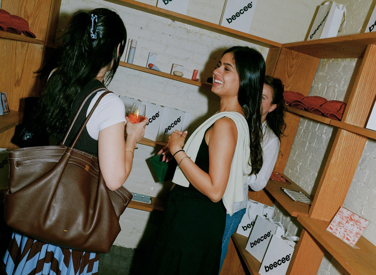 Women chatting in a shop with wooden shelves of beecee shopping bags and products