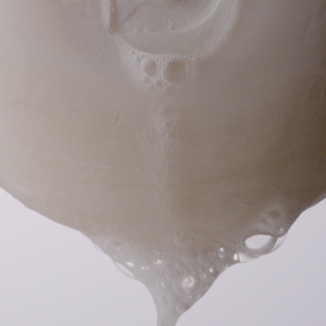Video of the well rounded soap bar bubbling and dripping suds against a white background. 